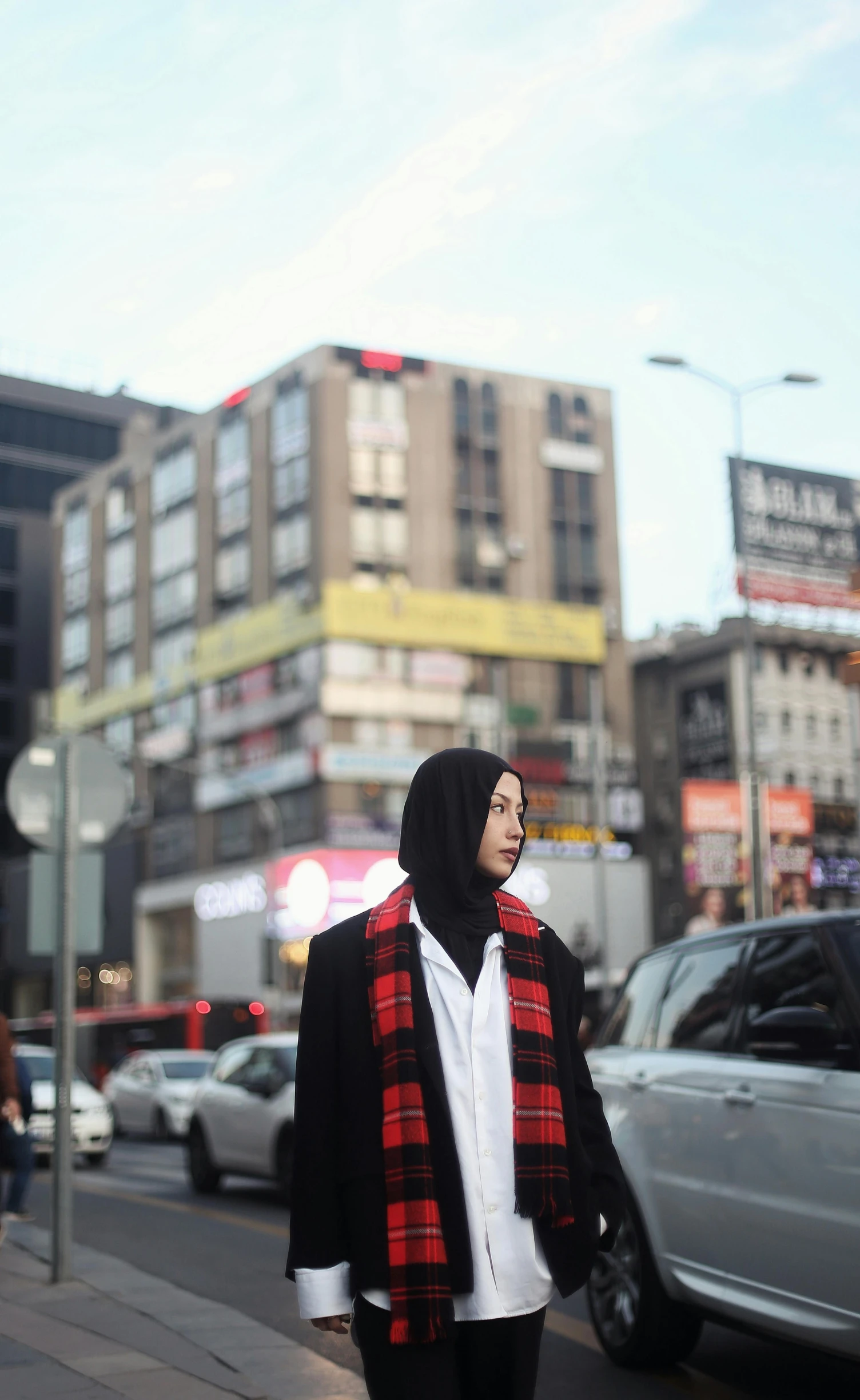 a woman standing on the sidewalk in front of a car