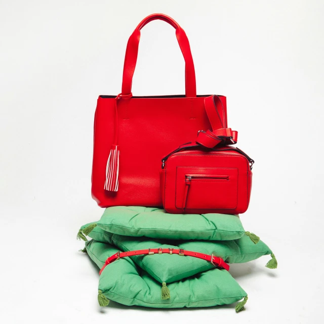 a red bag sits next to a green pillow