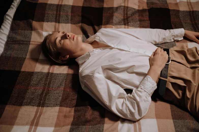 a young man sleeping on top of a bed covered in a blanket