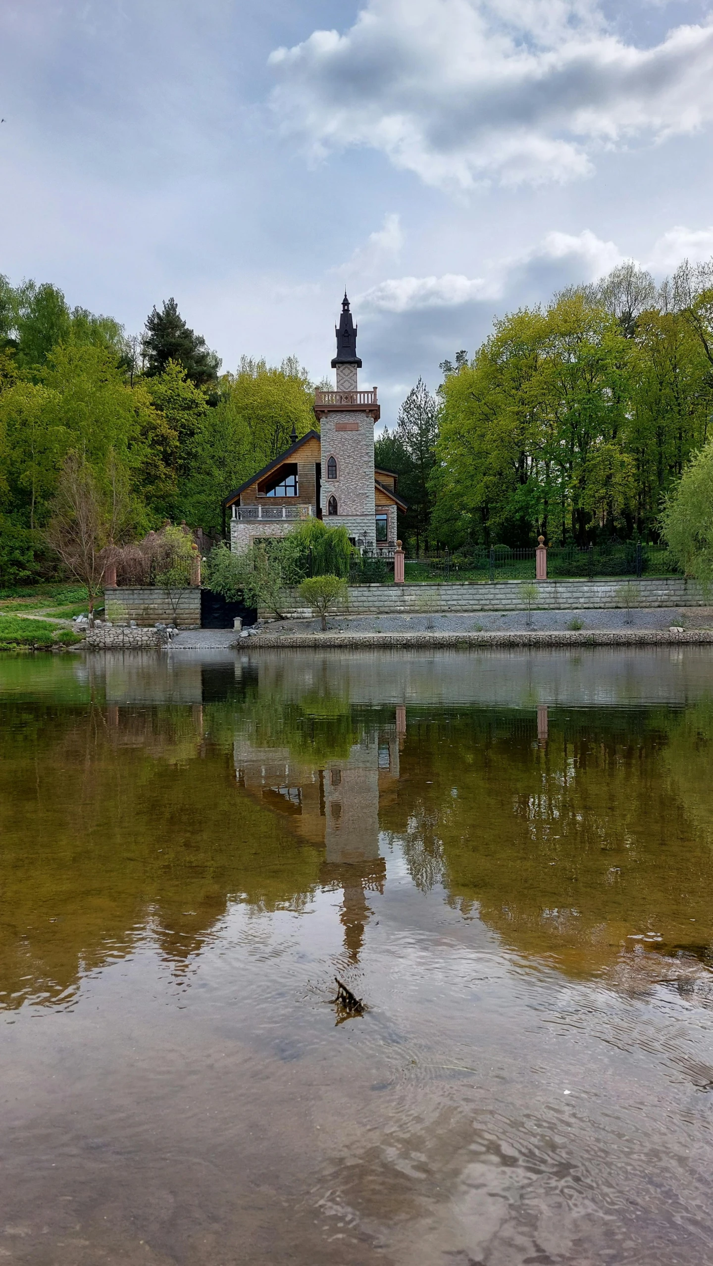 a clock tower on top of a tower on a hill by water