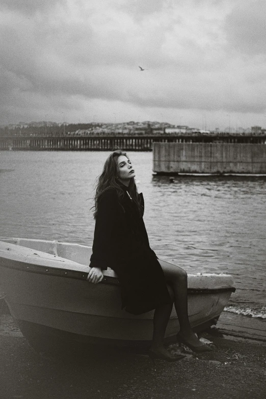 woman sitting in the front of a small boat by the water