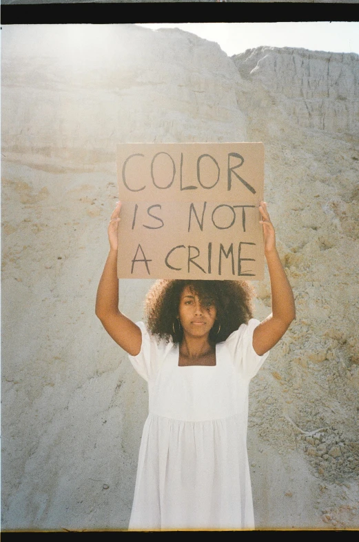 woman holding up a sign with the words, color is not a crime