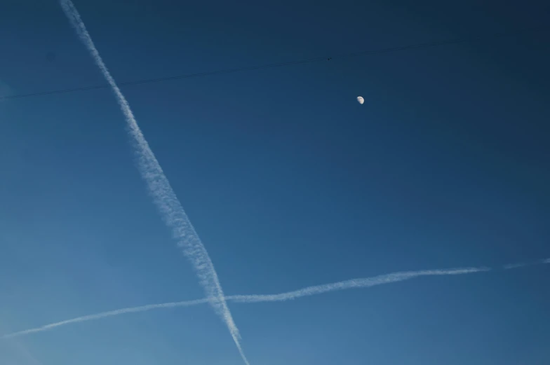 a contrail and the moon in the sky