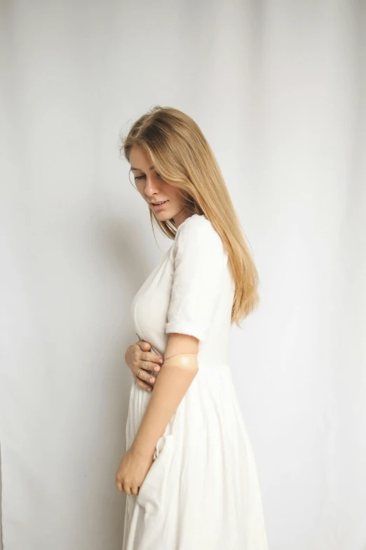 a woman standing next to a white wall posing for a po