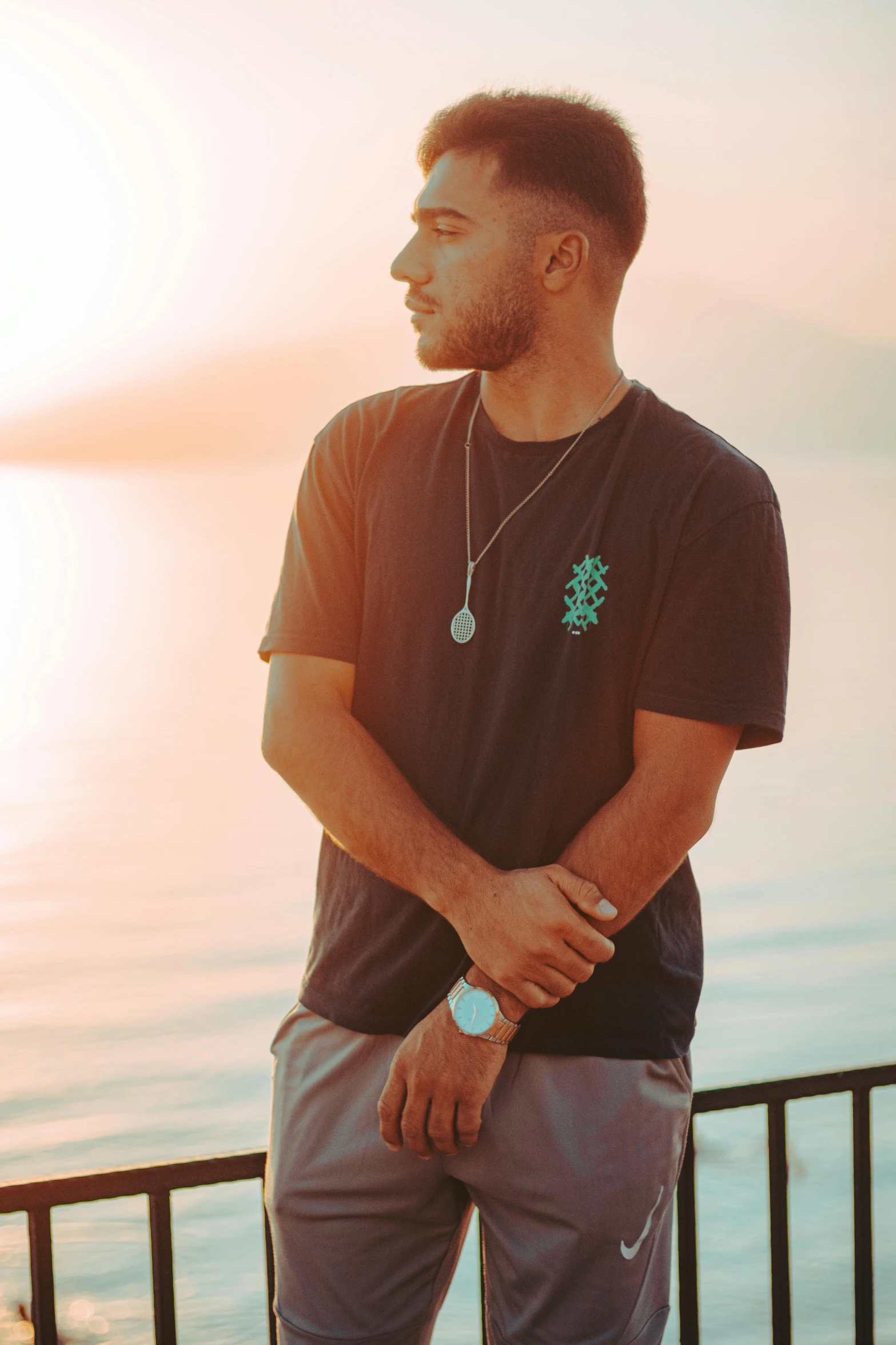 a man standing next to a fence in front of the water