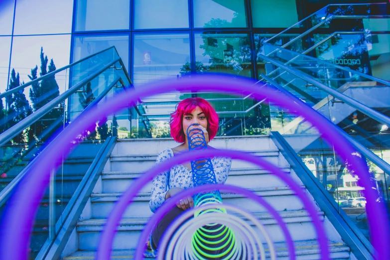 a woman wearing pink hair standing on stairs with circular items in her hand