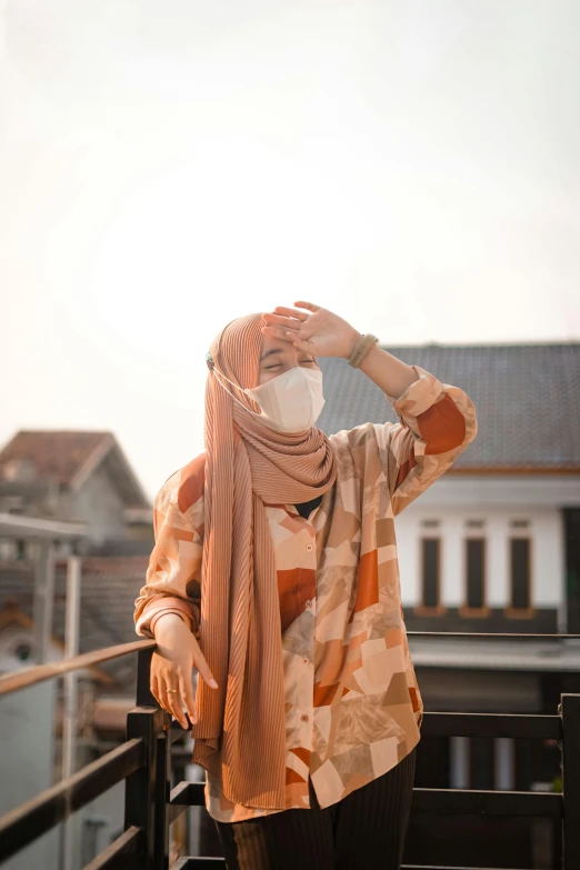 a woman standing on a metal rail wearing a scarf