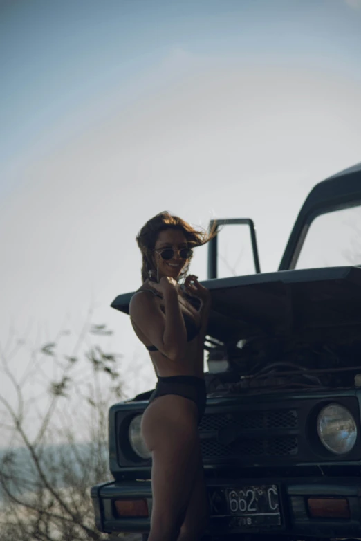 a women in black underwear standing next to a car