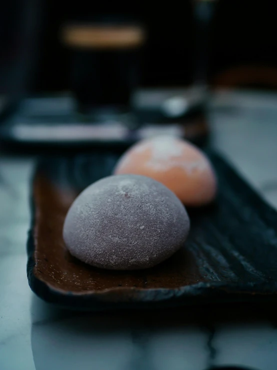 two dark colored stones are sitting on a tray