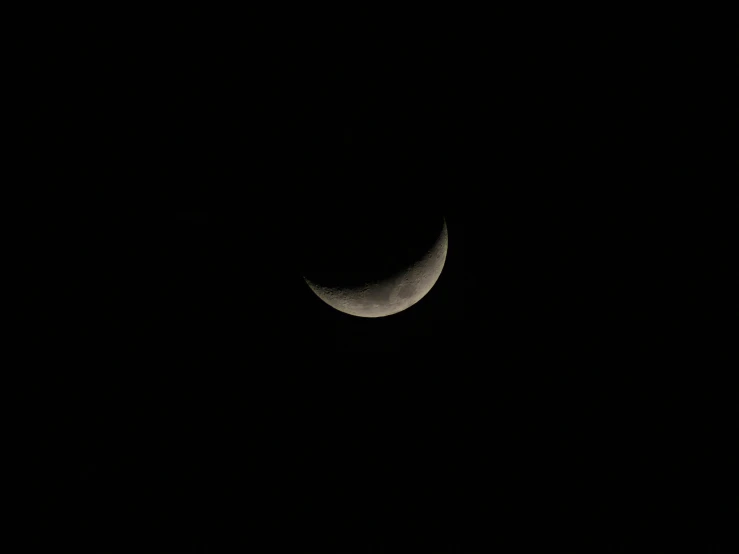 a crescent moon with dark skies in the background
