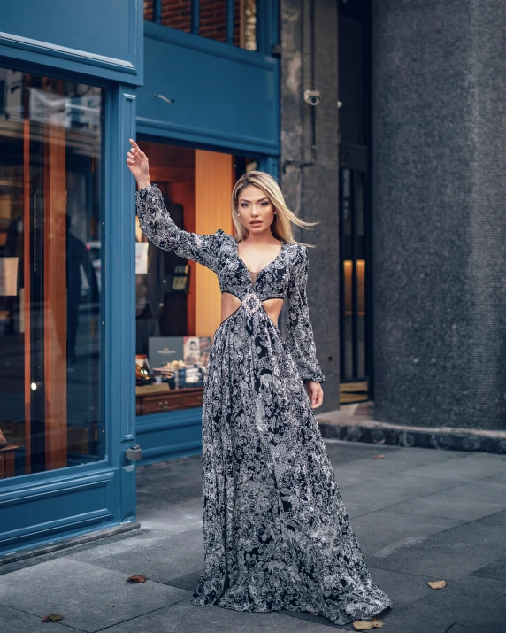 a woman stands on a sidewalk in a long dress