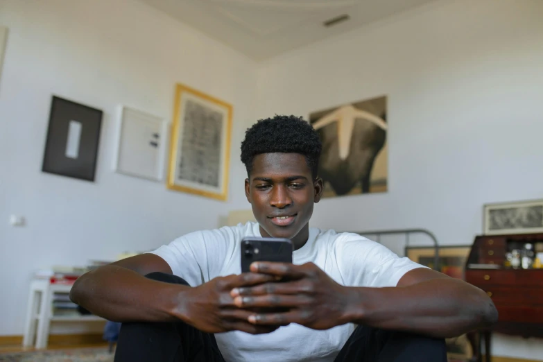 a man holding a cell phone while sitting on a chair