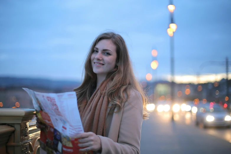 the lady smiles while reading a news paper