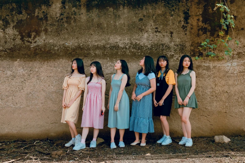 four girls stand in front of an outside wall and pose for a picture