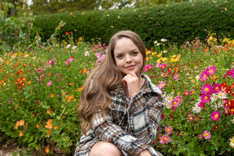 the  is sitting in front of a flower garden