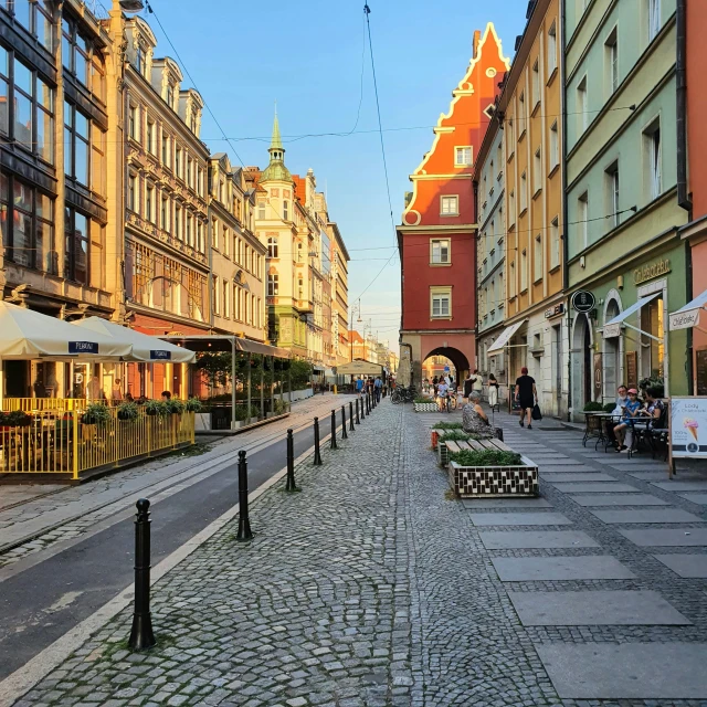 a cobblestone street lined with buildings and people sitting at tables