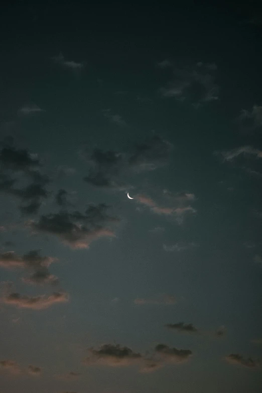 the moon is shining in a cloud filled sky