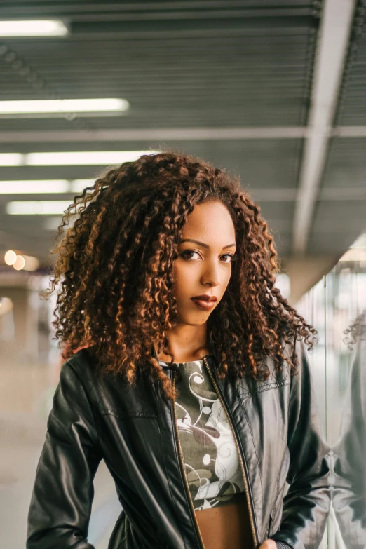 woman in leather jacket and floral shirt in an empty room