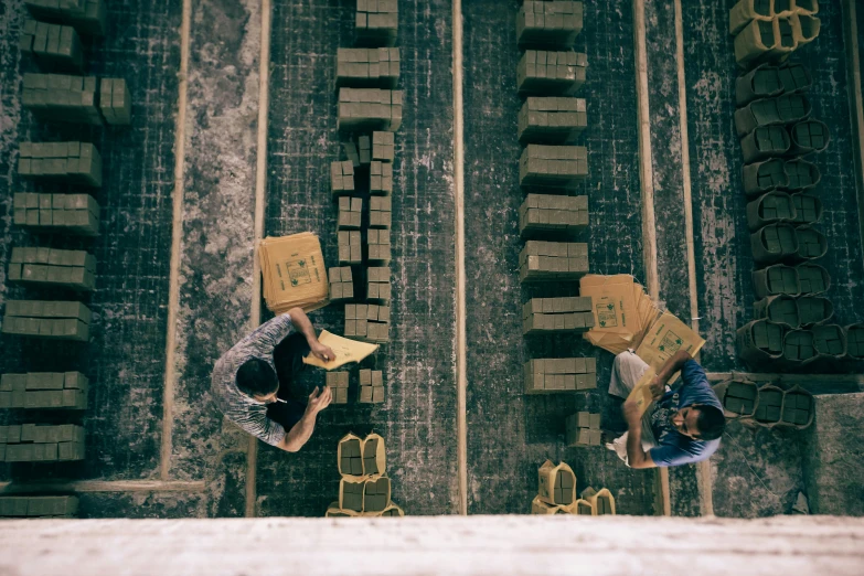 two men with boxes are looking over a wall