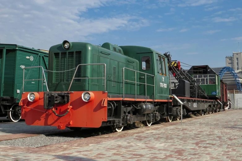 a green train engine on a track with many other trains