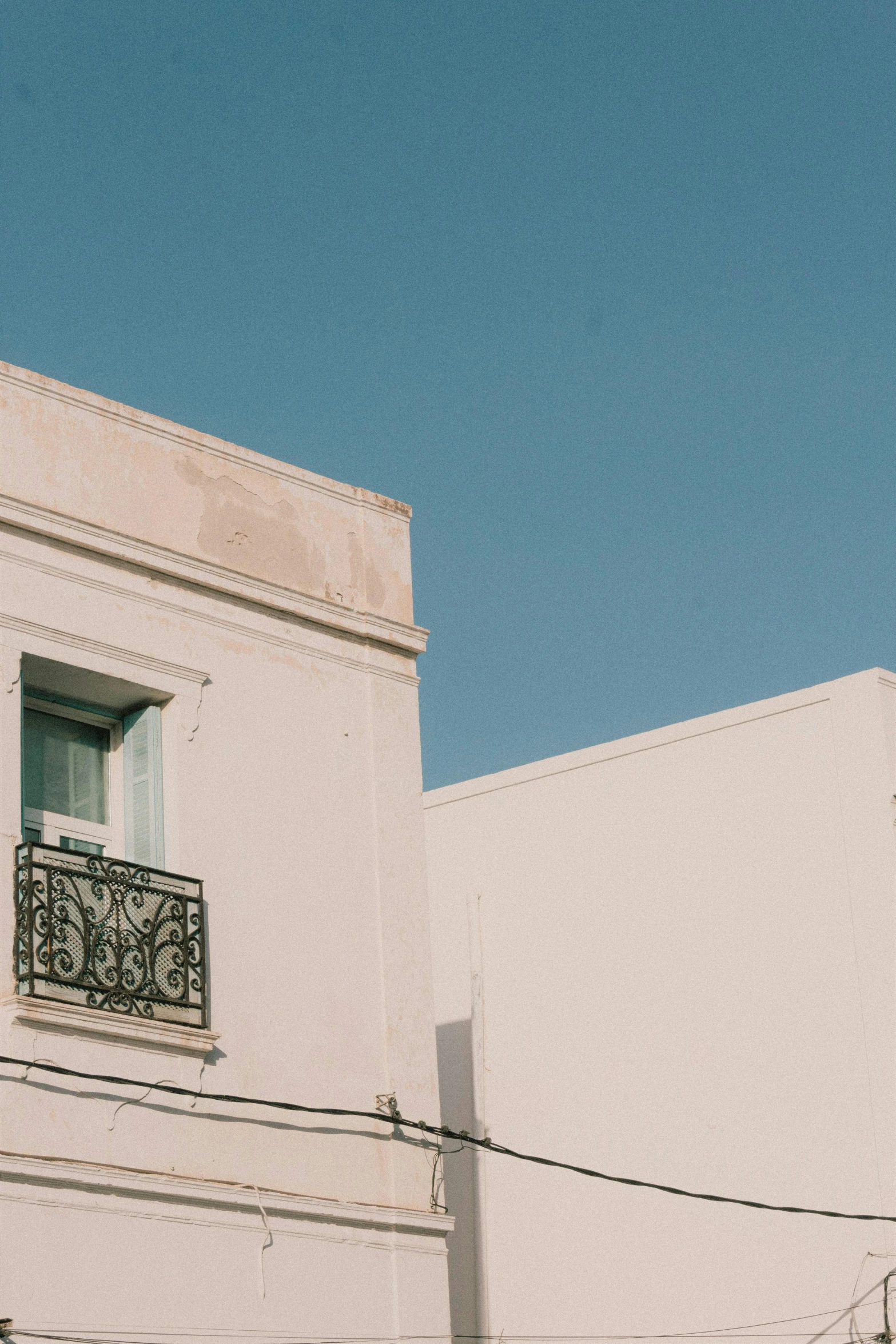 the side of a white building has a balcony and window