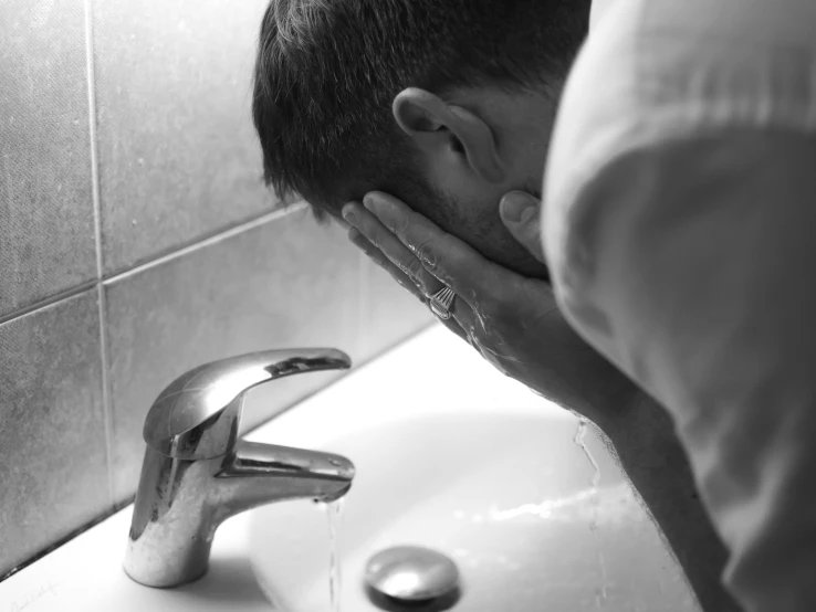 a man standing in front of a bathroom sink