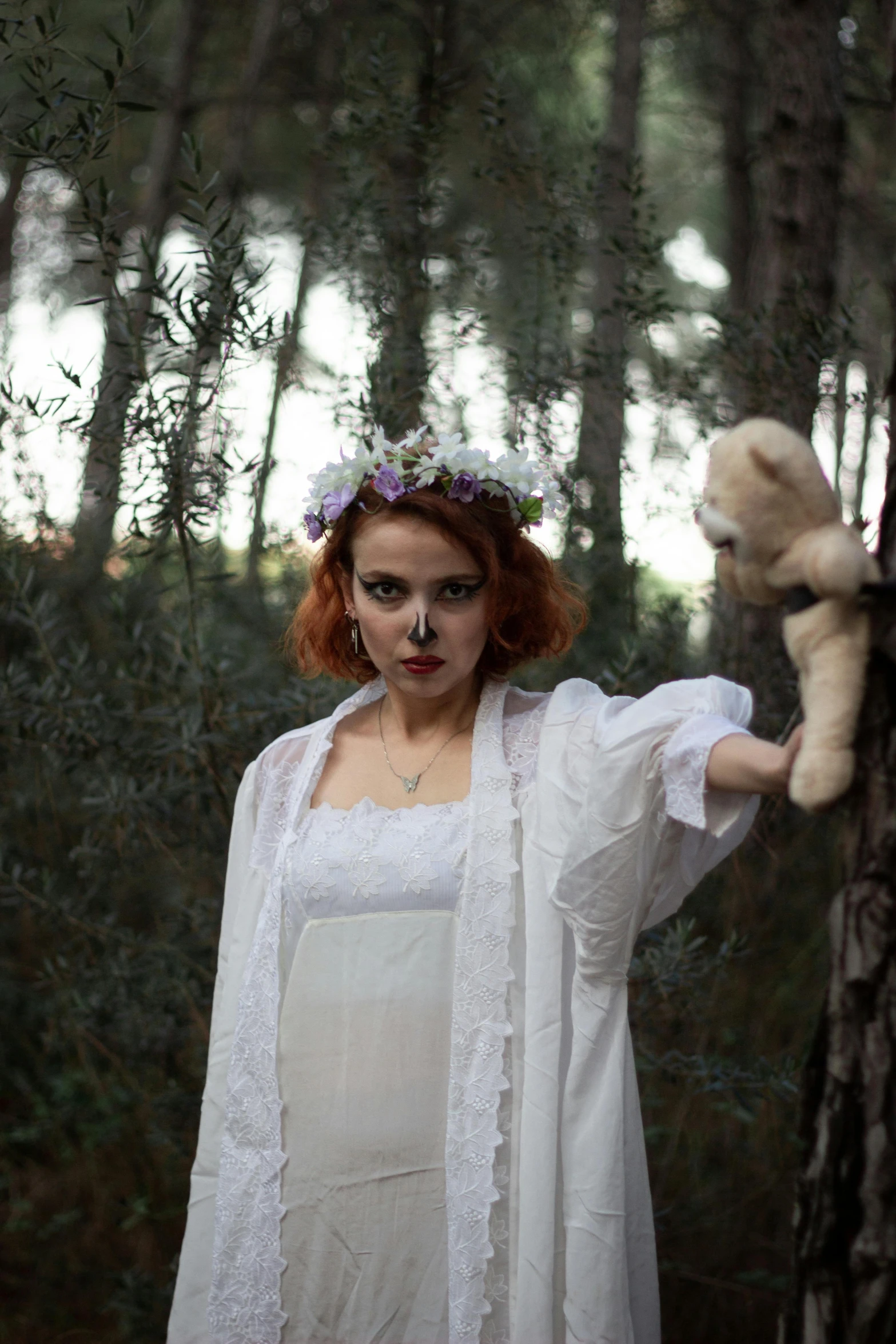 a woman dressed up in white holding a brown teddy bear