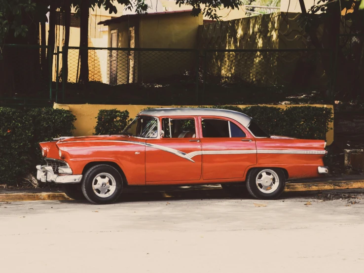 an orange car with a white top parked in front of a building