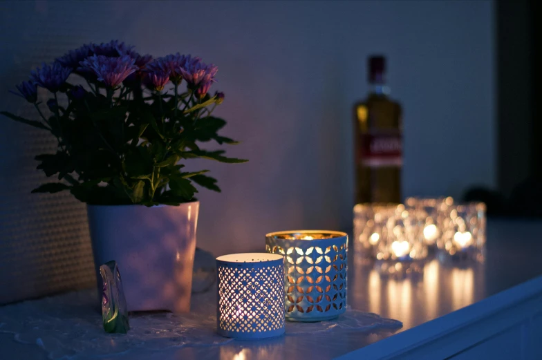 lighted candles and a potted flower sit on a shelf