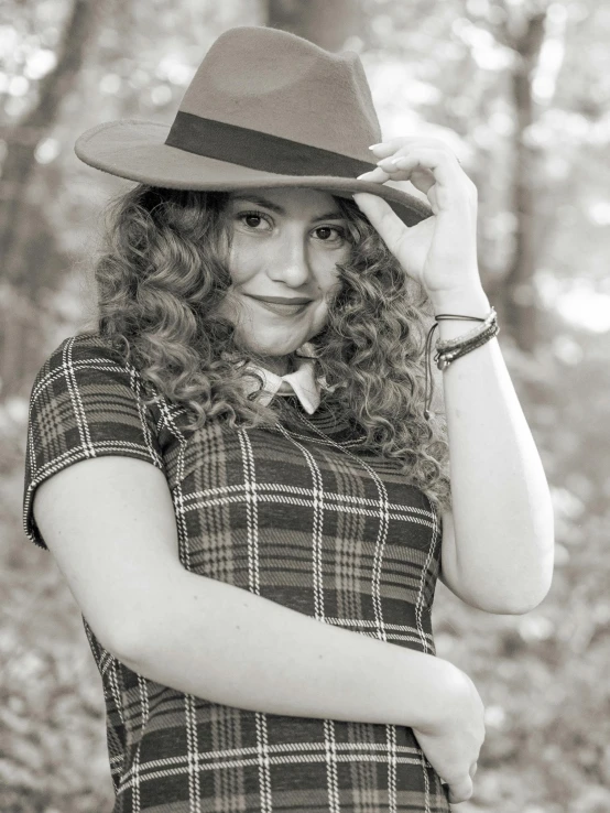 a beautiful woman standing in the woods wearing a hat