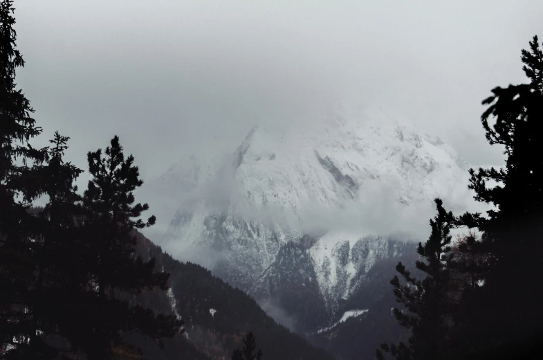dark and cloudy view of a mountain with trees around it