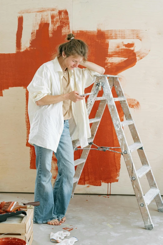 a woman is painting an orange wall