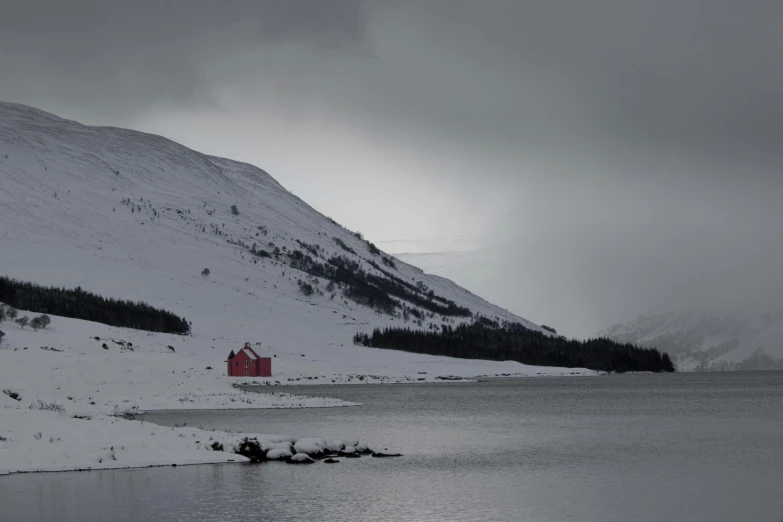 a lone house sitting in the snow by the mountains