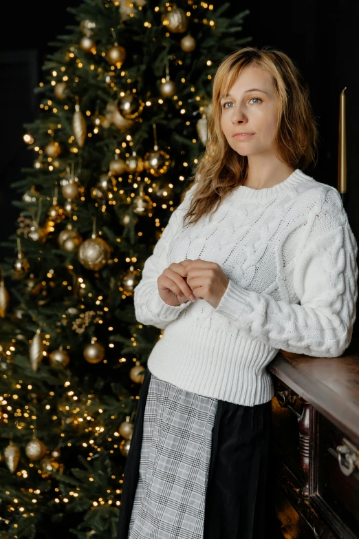 a beautiful blonde woman standing by a christmas tree