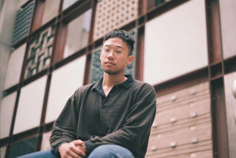 a man sits outside on the concrete of an urban building