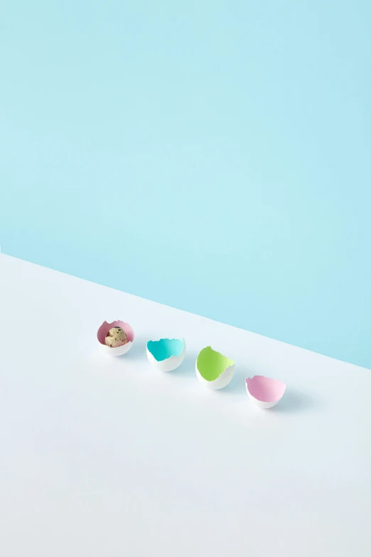 three different colored bowls sit on a white surface