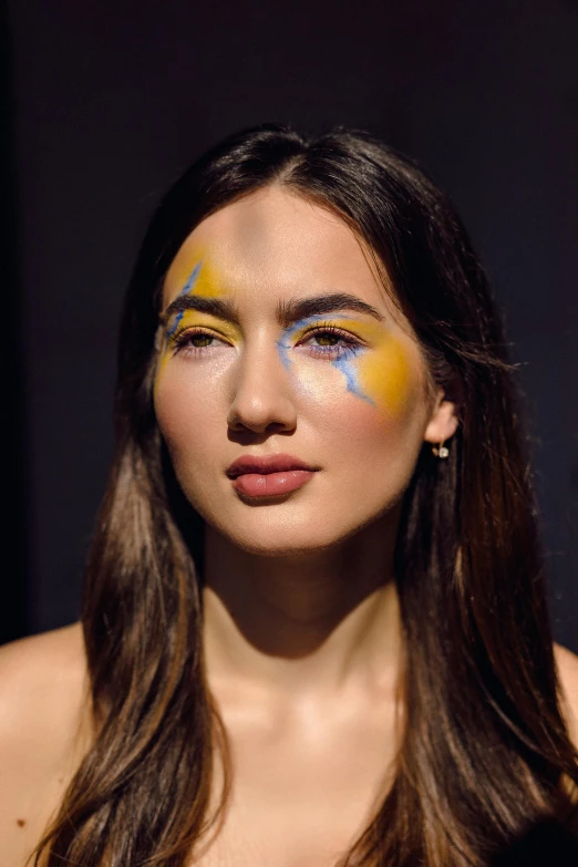 the woman with painted yellow and blue makeup on her face