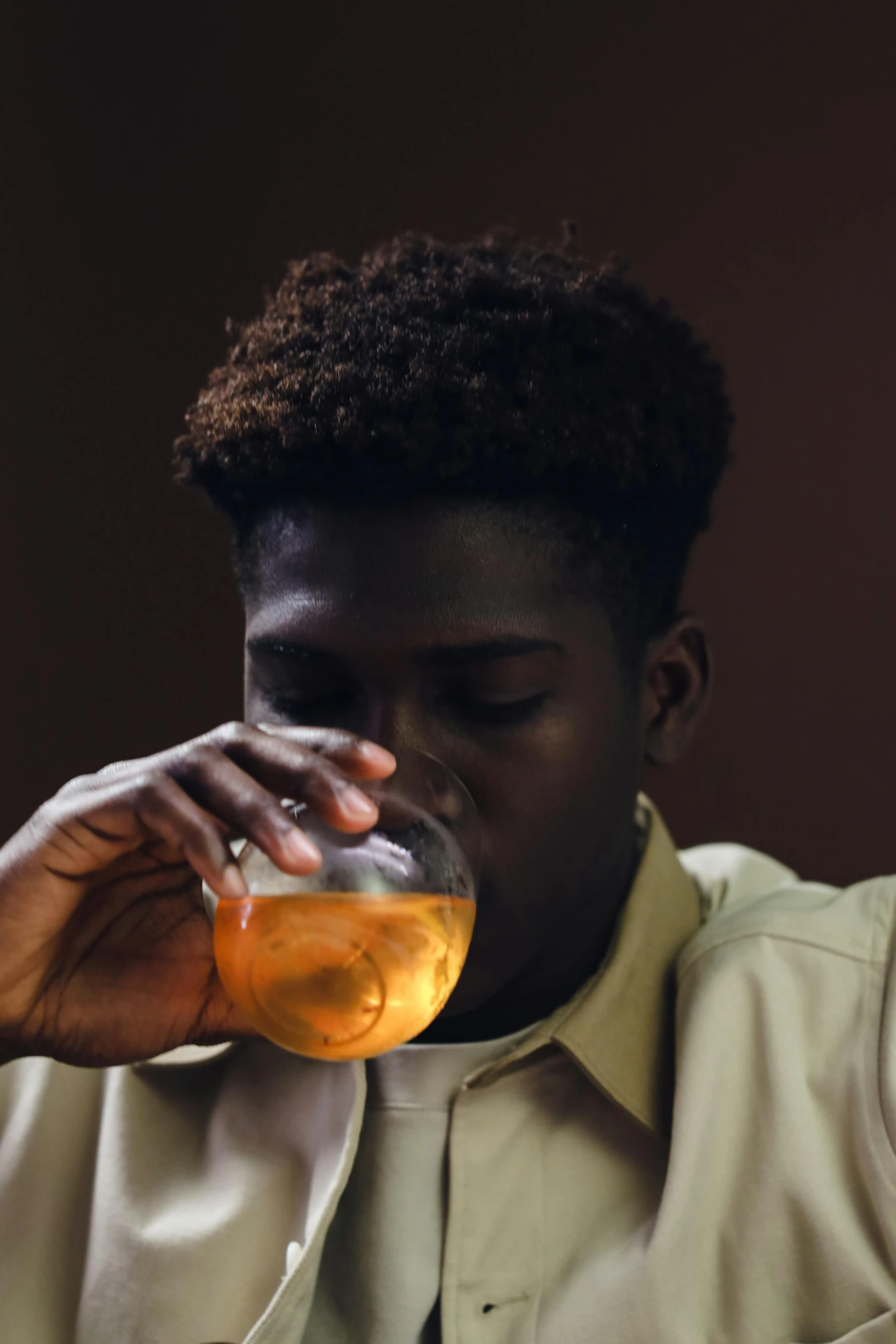 a young black man sitting down drinking a beer