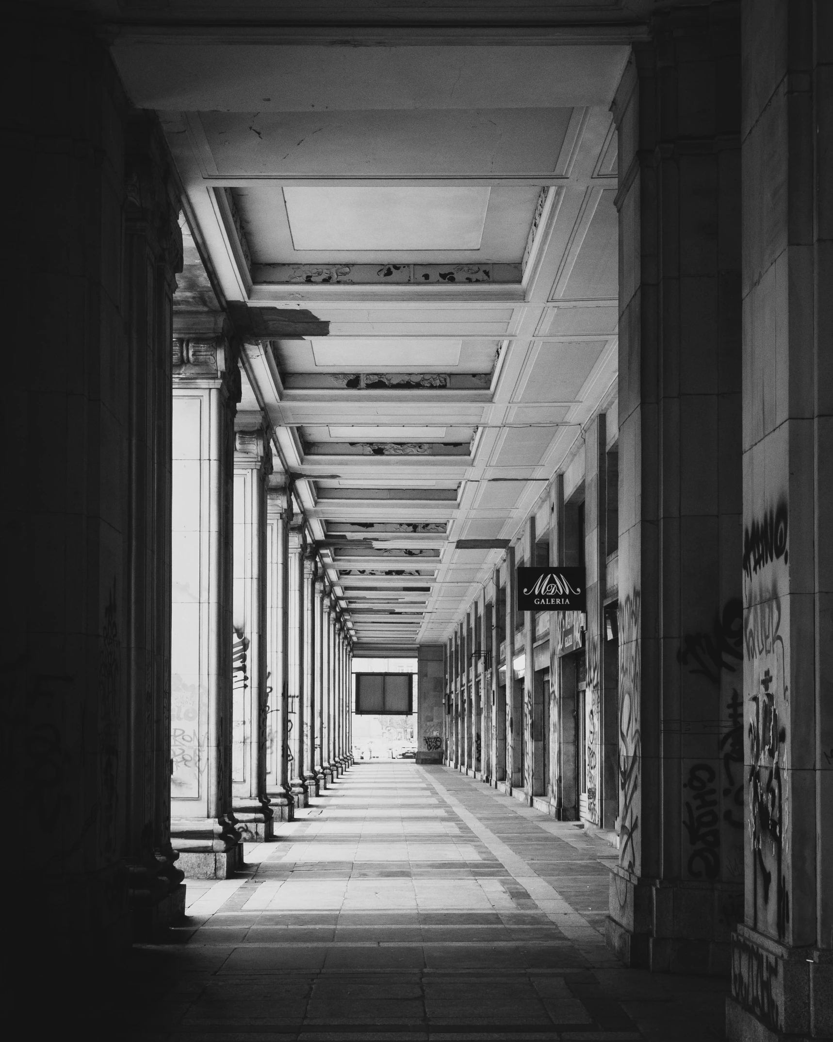 an empty hallway with many columns and graffiti on the walls