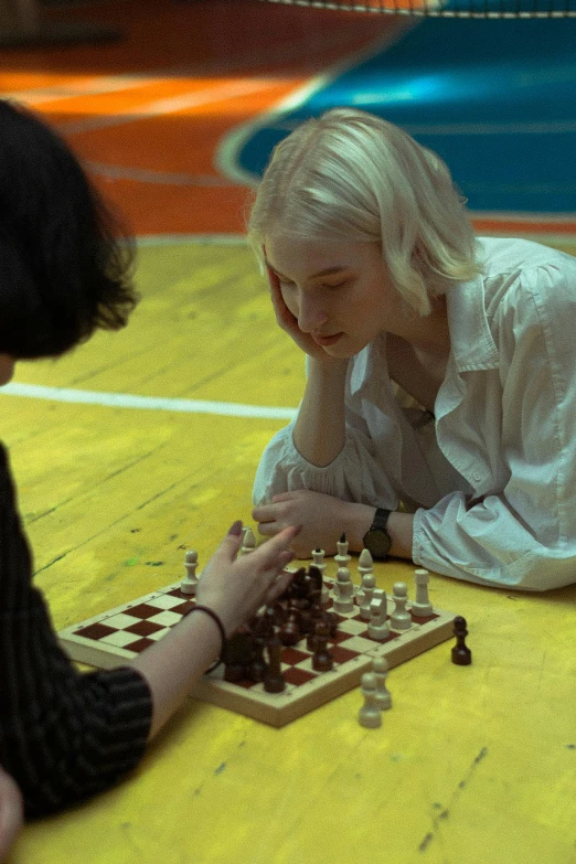 a woman and boy play chess on the floor