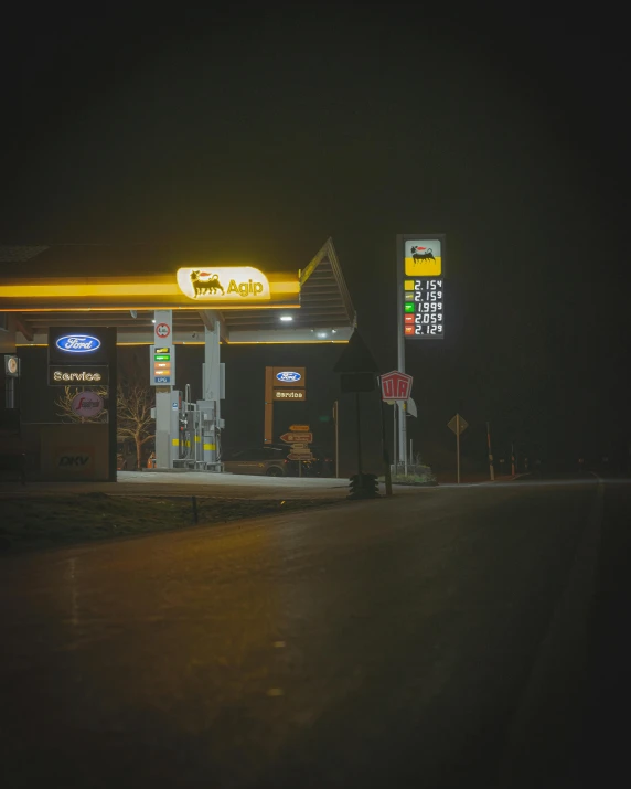 a gas station with gas prices on the front and gas signs at night