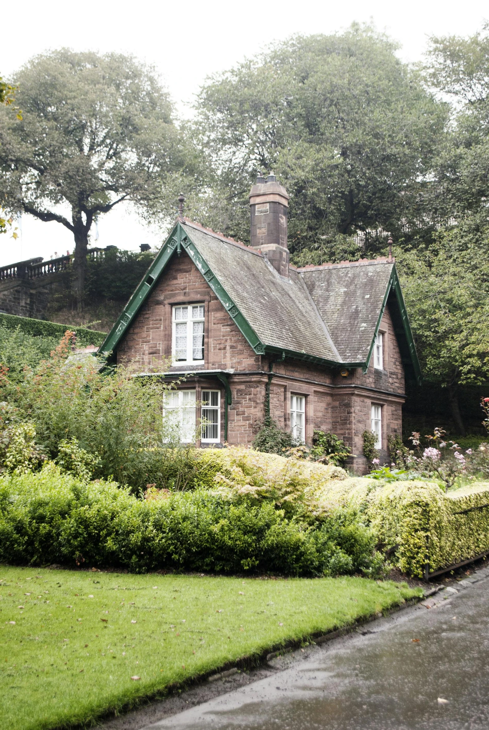 a brown house sitting on the side of a lush green hillside