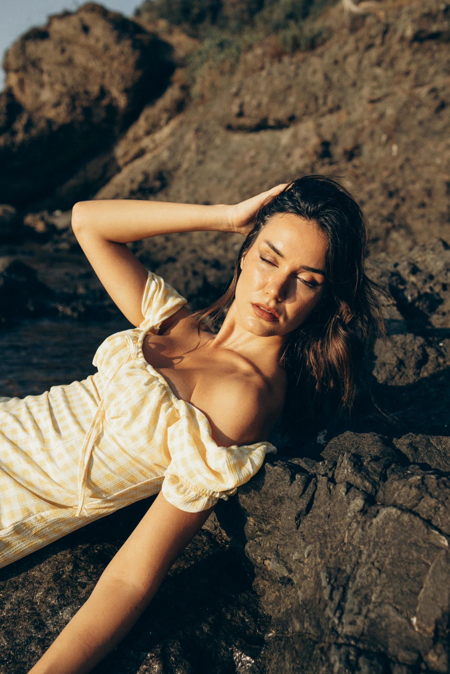 a young woman posing on some rocks at the beach