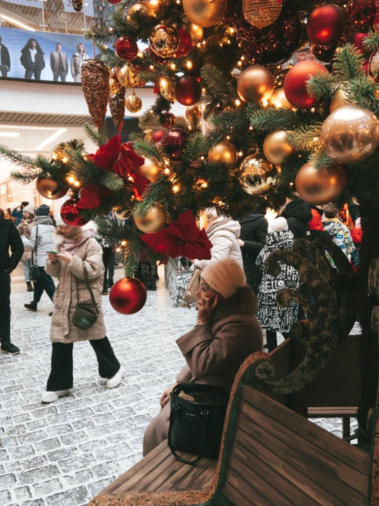 a woman sits on a bench in front of christmas decorations