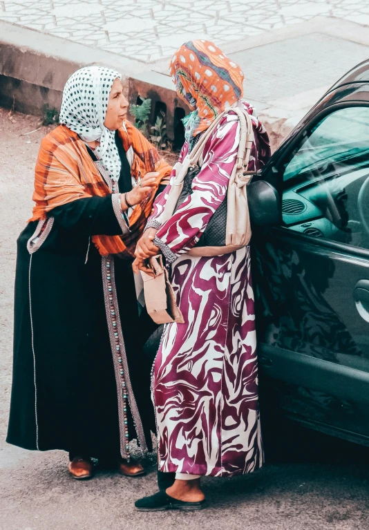 two women in headdresses boarding a black car