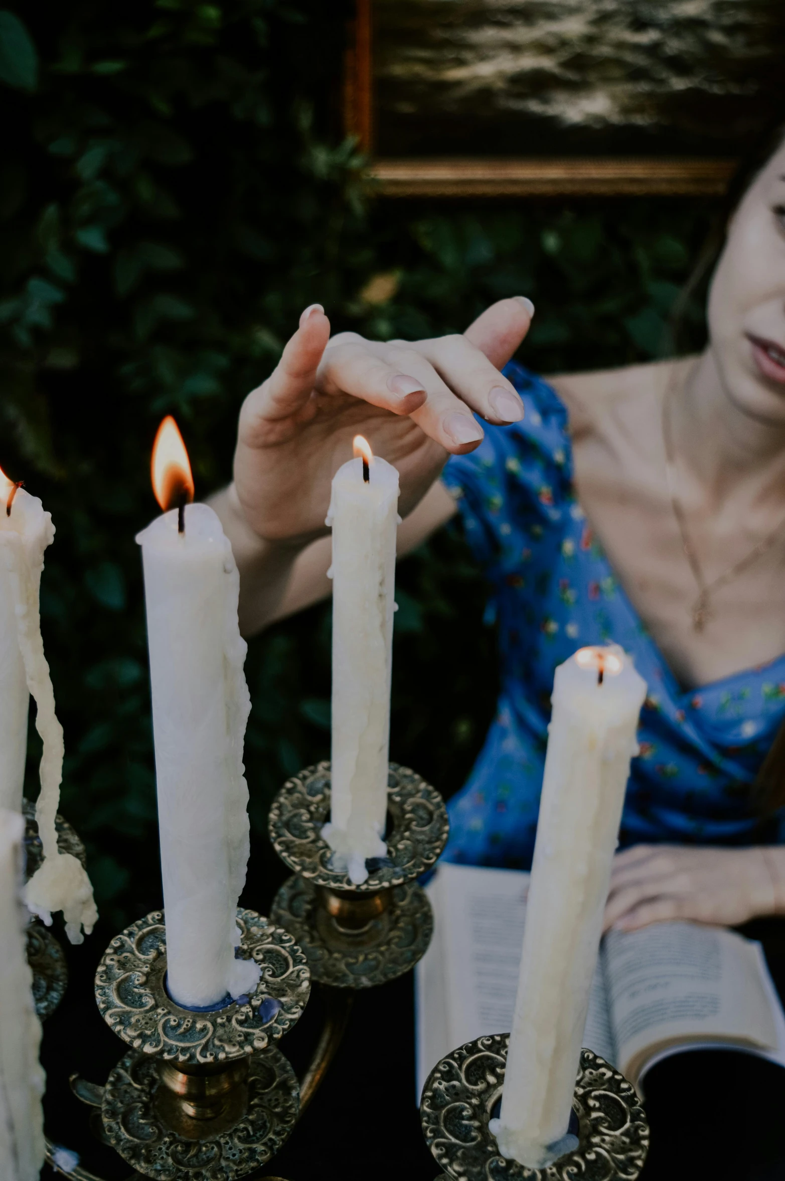 a woman holds her hands out towards candles