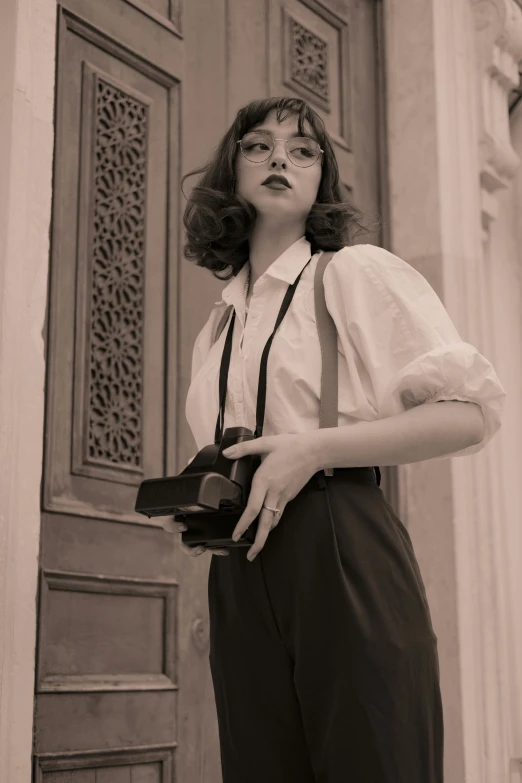 woman posing for picture near building with camera in hand