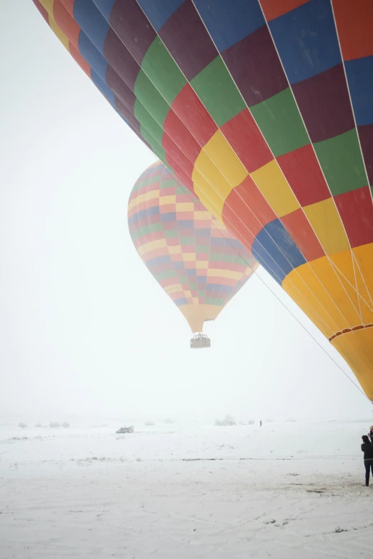 several colorful  air balloons floating over a snow covered ground
