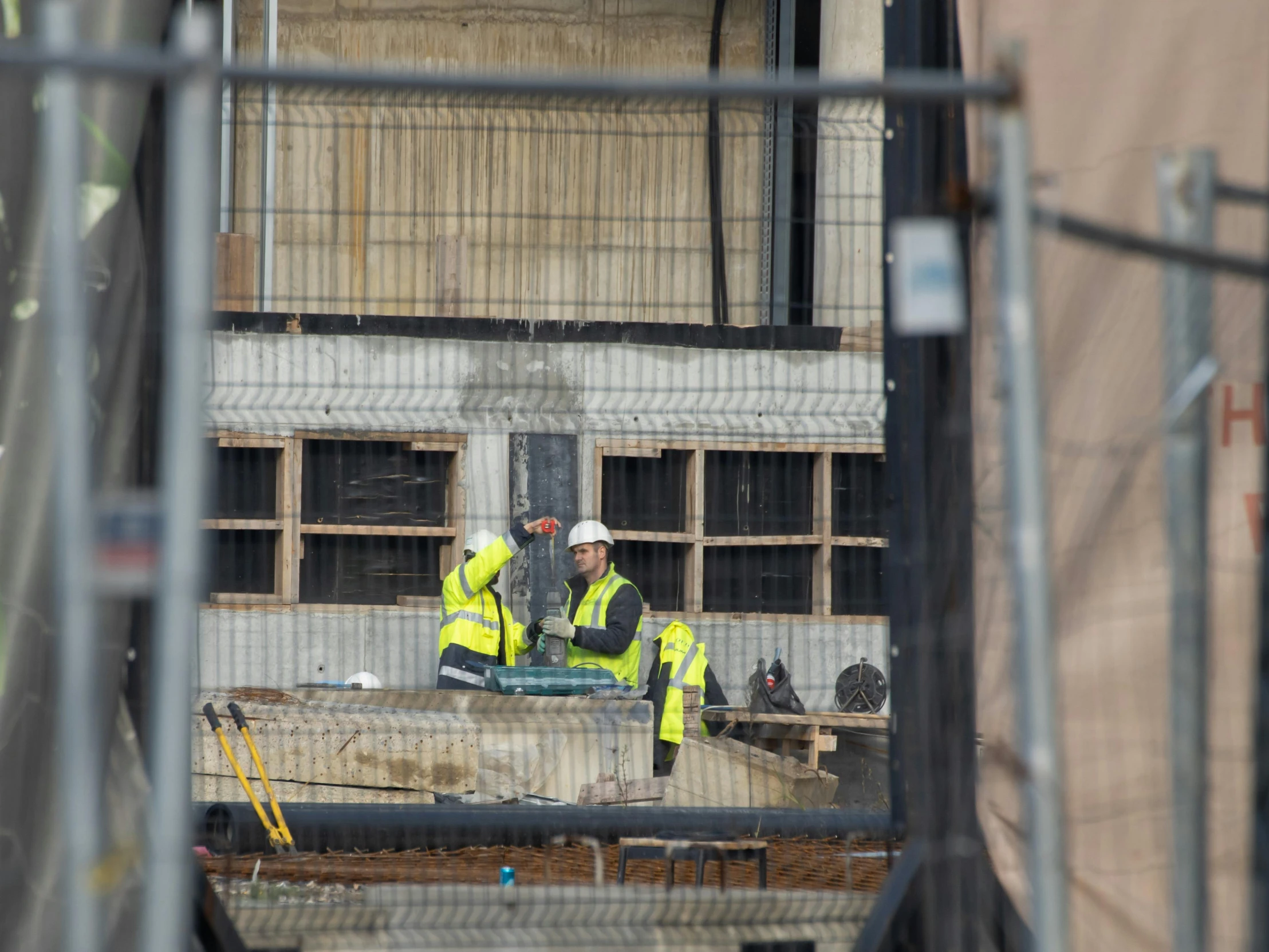 two construction workers with construction material in the background