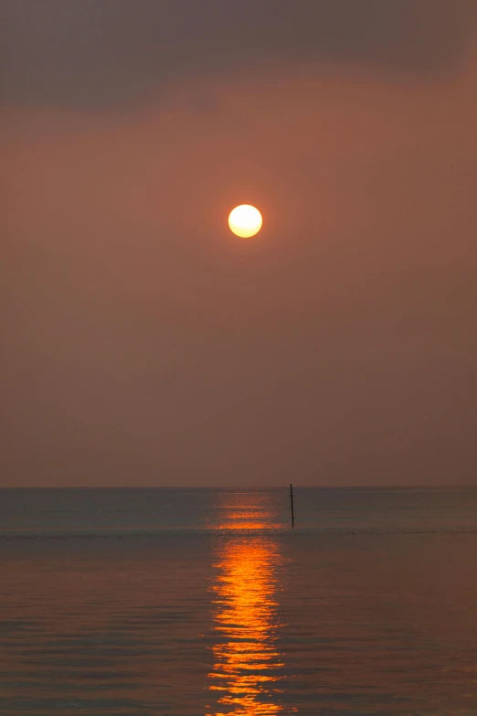 the sun is setting over the horizon and reflecting on the water